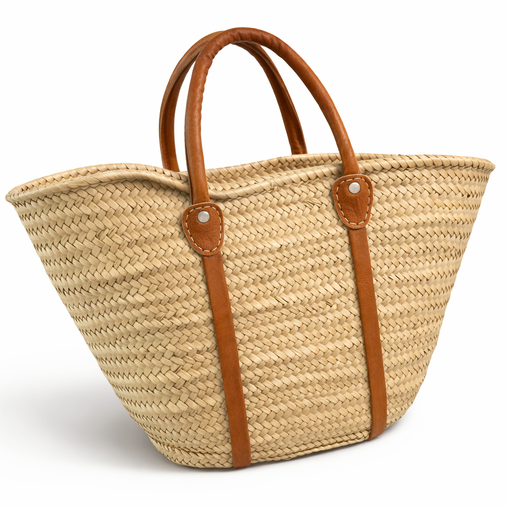 Woven straw tote bag with brown leather straps on a white background