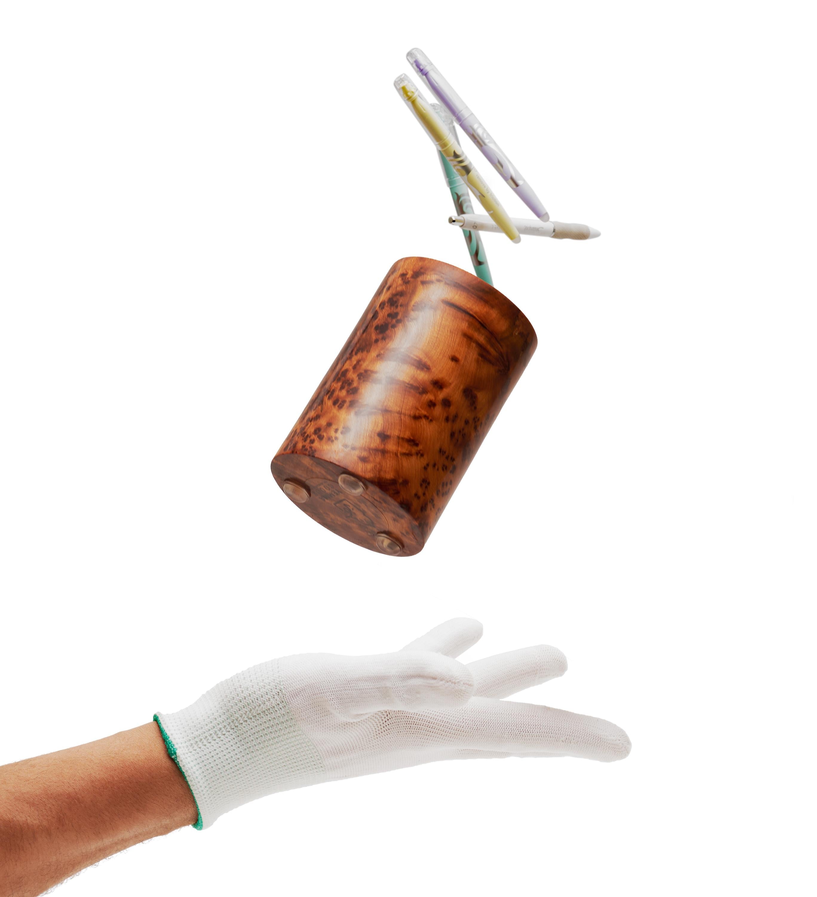 Wooden pens holder with pens flying on the air, thrown by a gloved hand against a white background
