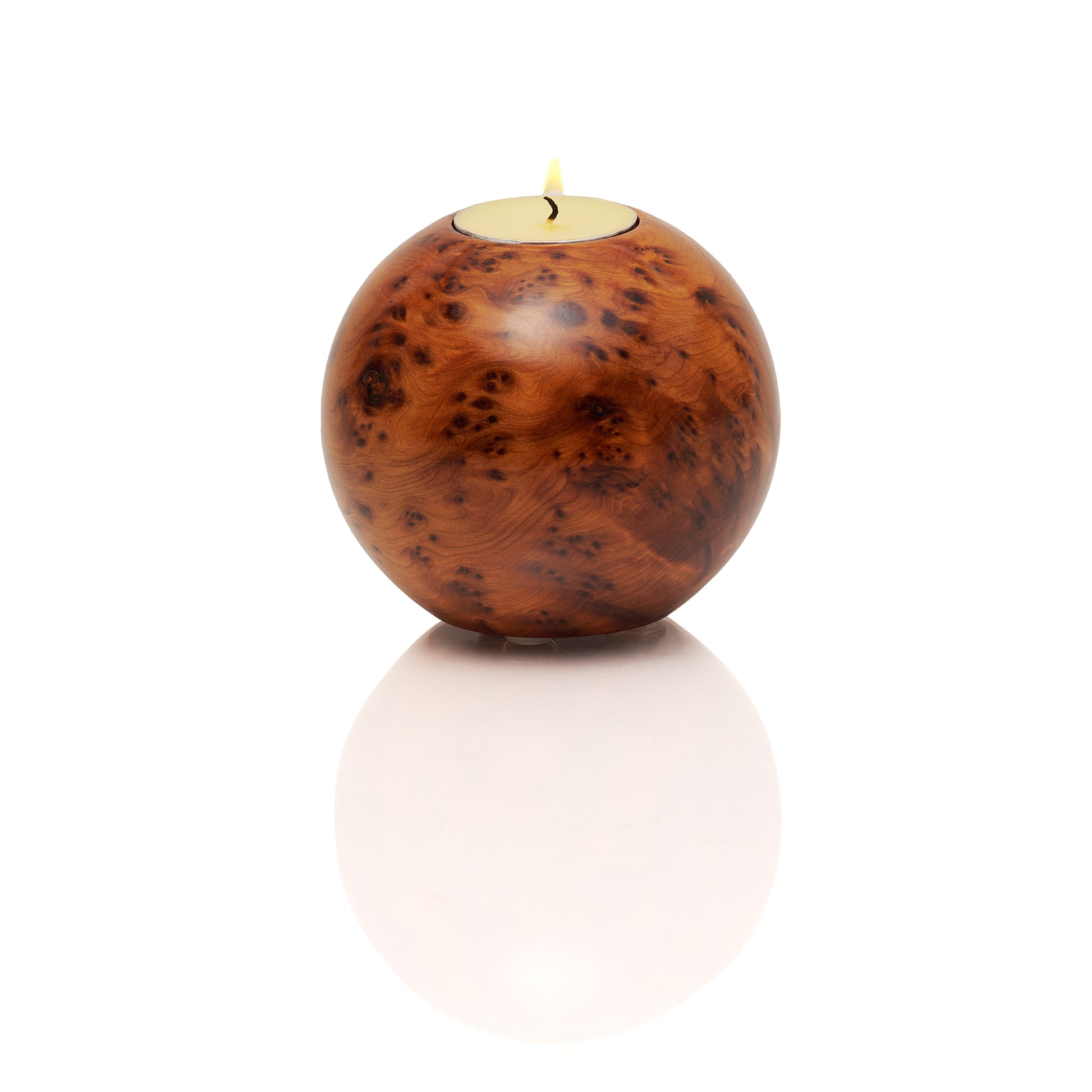Wooden sphere candle holder with a lit tea light candle on a white background surface
