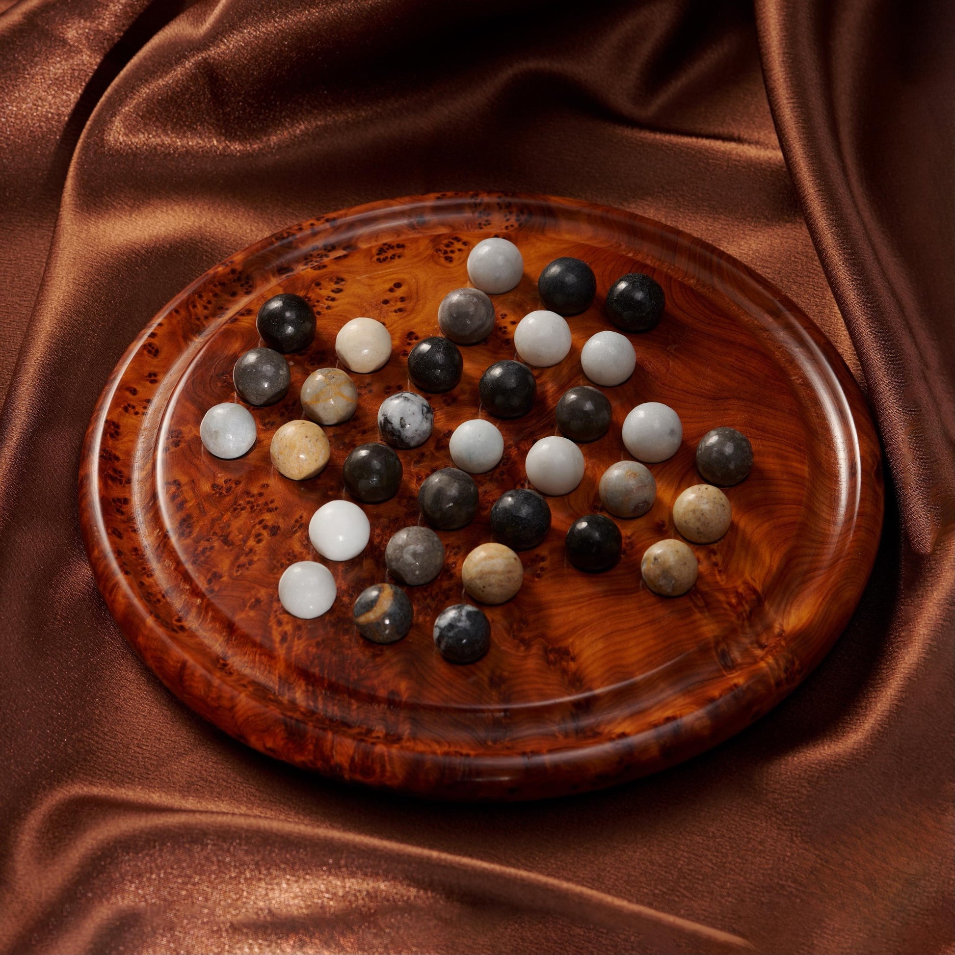 Wooden plate with multicolored stones on a brown fabric background