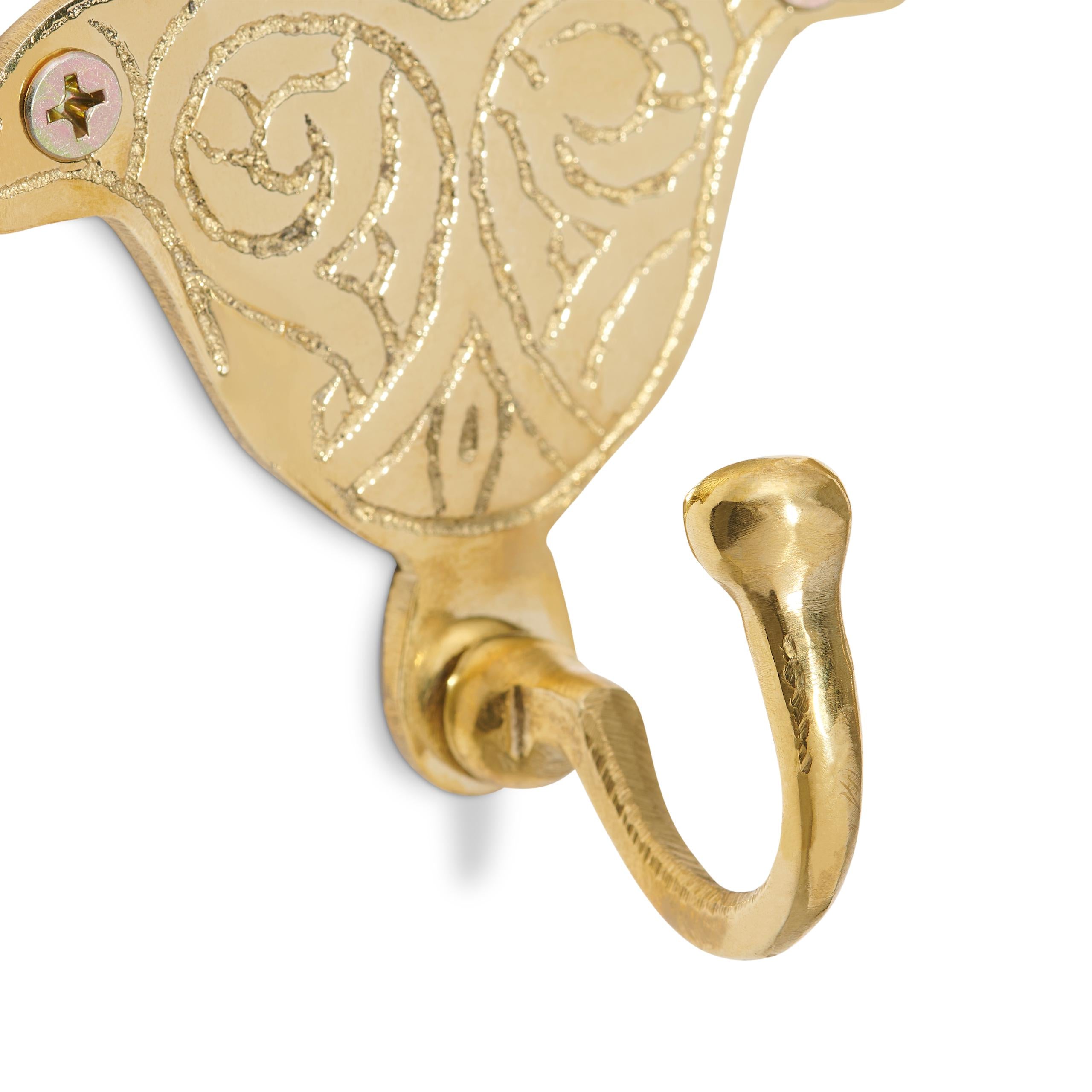Decorative brass hamsa hook with intricate patterns on a white background