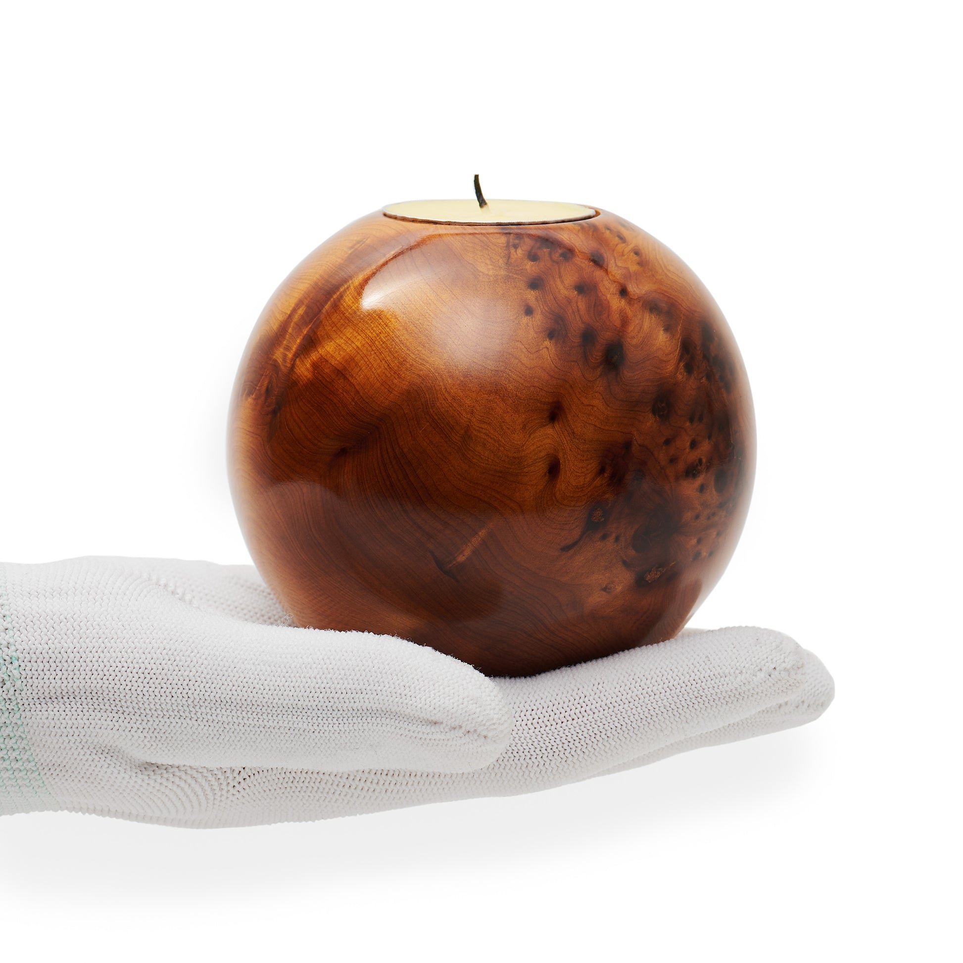 Wooden ball-shaped candle holder on a white hand with a white background