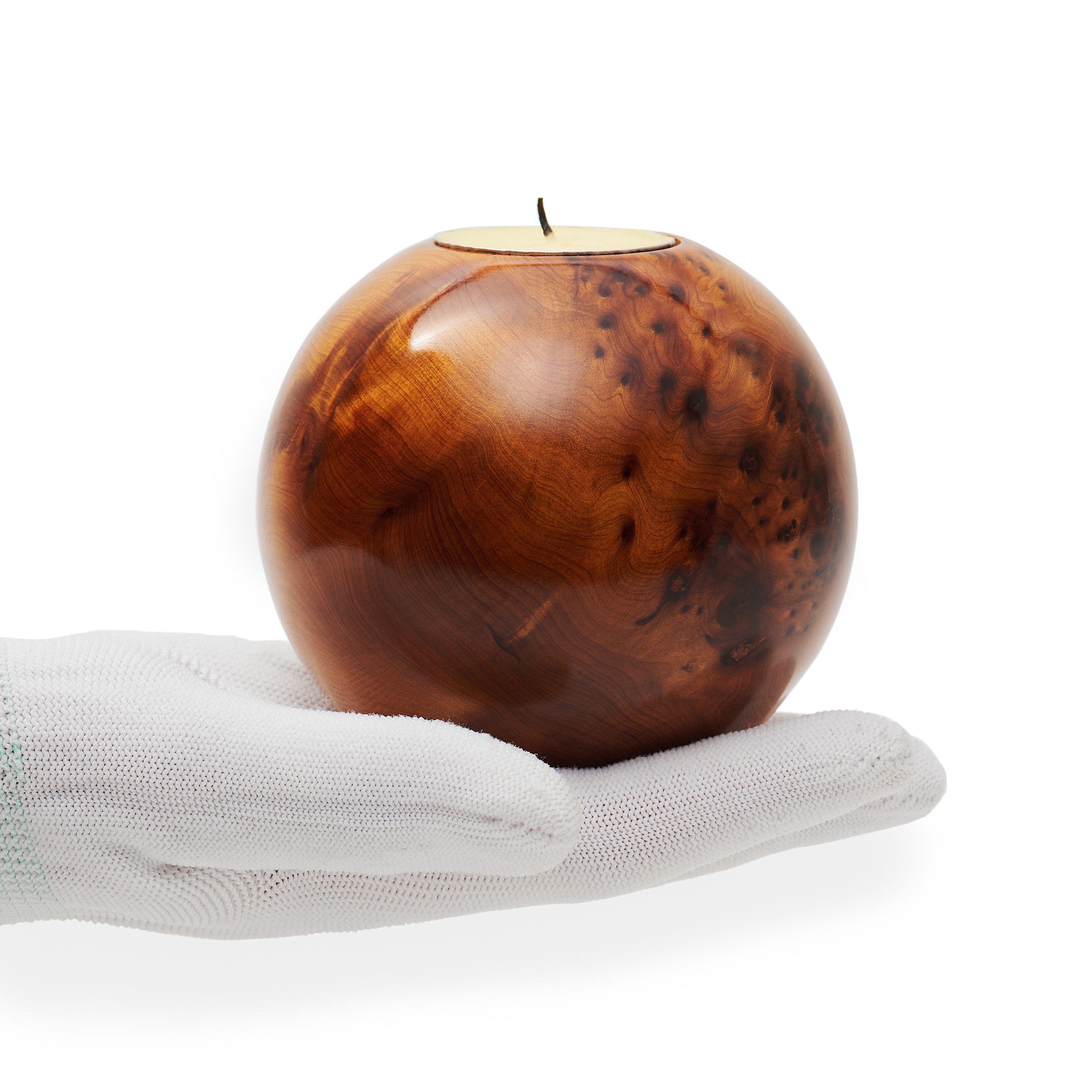 Wooden ball-shaped candle holder on a white hand with a white background