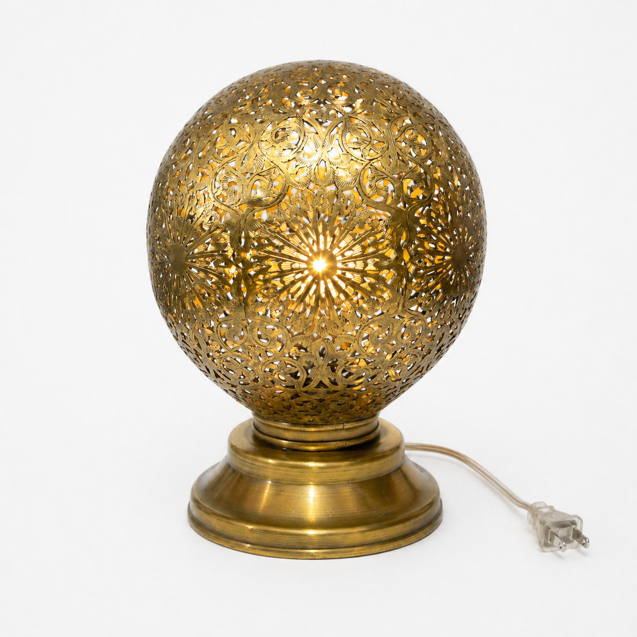 Decorative brass table lamp with intricate design on a white background