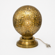 Decorative brass table lamp with intricate design on a white background