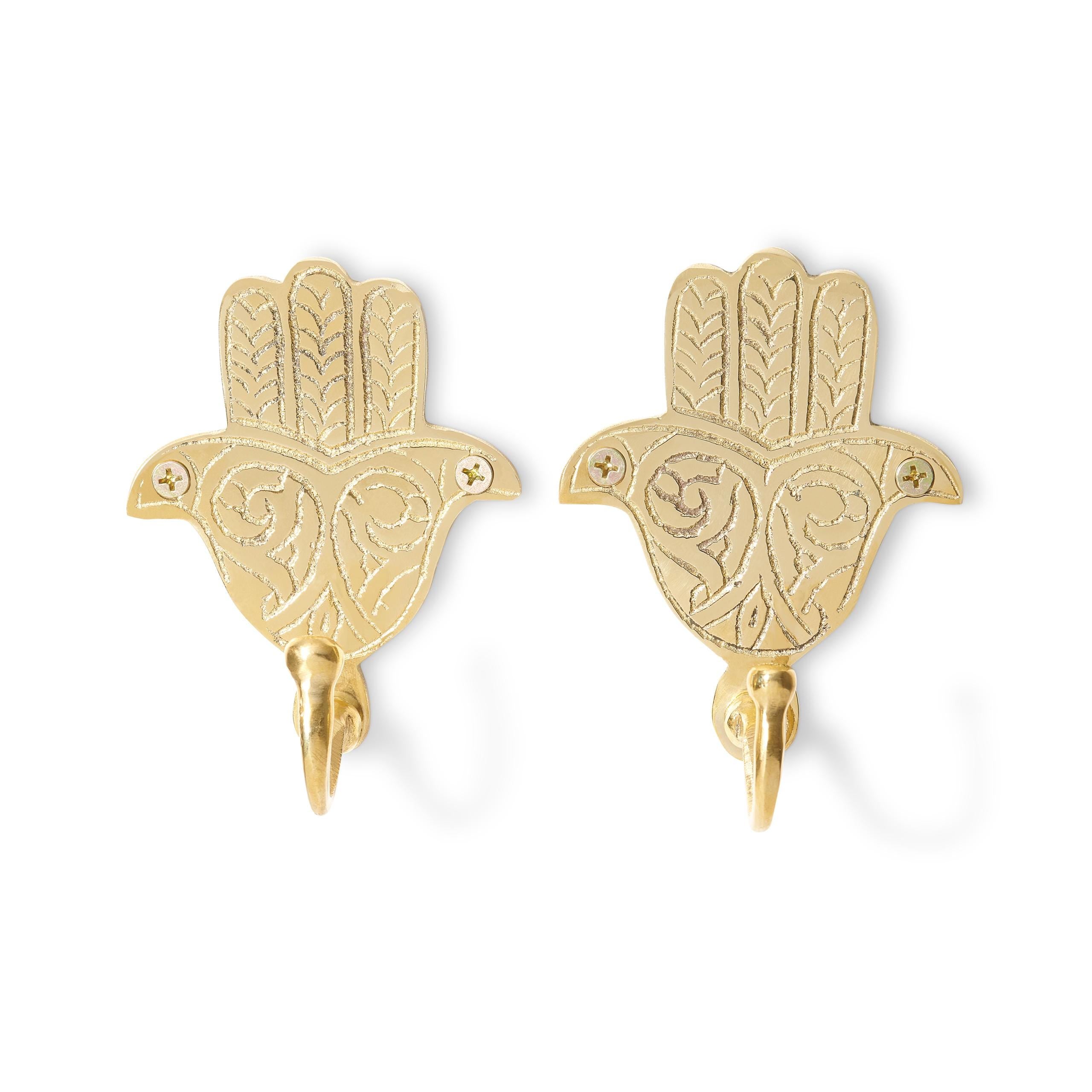 Two brass Hamsa hand wall hooks on a white background