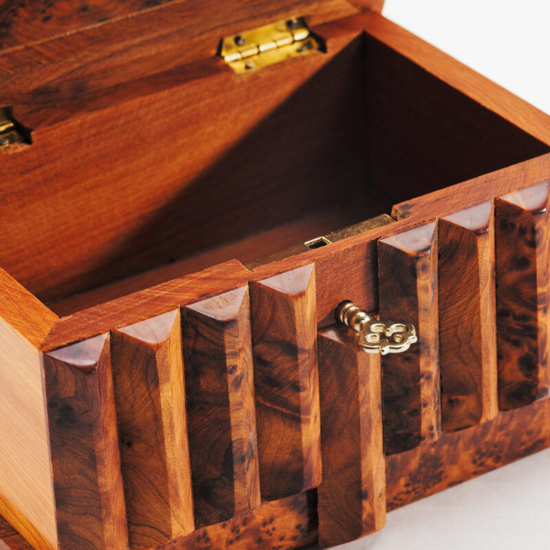 Close up shot of thuya wooden jewelry puzzle box showing the key inserted in lock, decorative design
